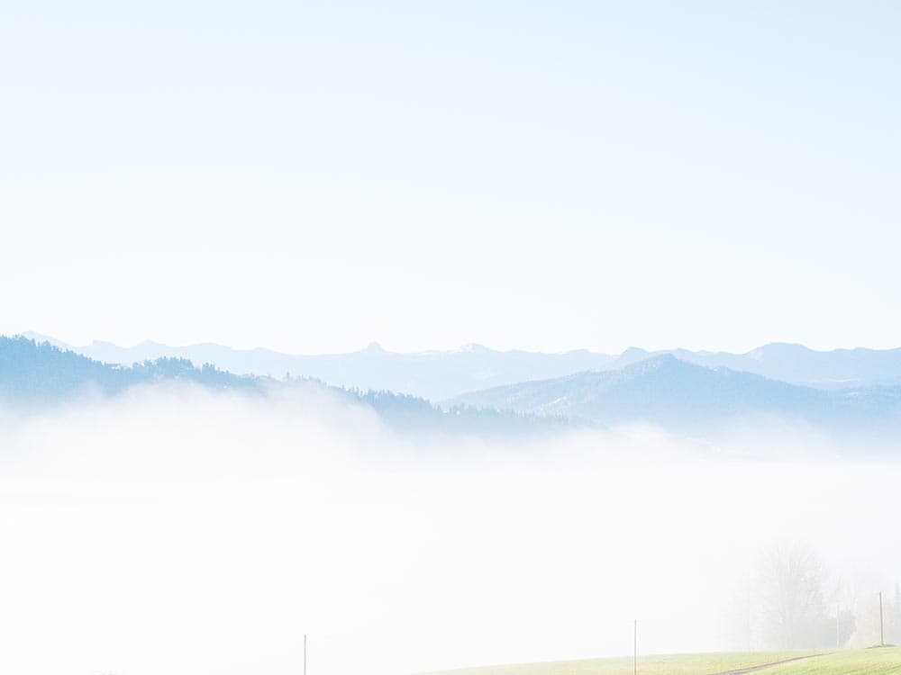 Nebelmeer über dem Tal, aus dem nur die blauen Bergkämme herausragen