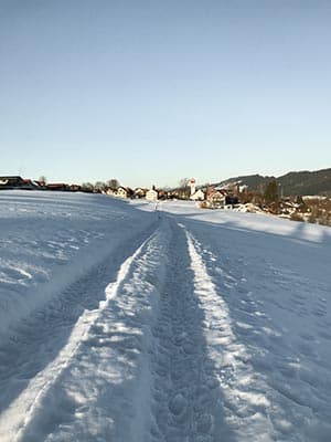 Ausgetretene Spur im Schnee, die auf die Häuser von Scheffau zuführt