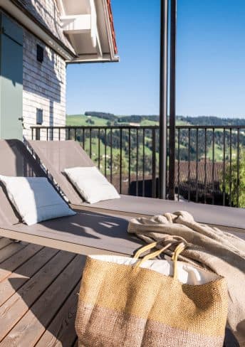Zwei Sonnenliegen auf einem Balkon der Alpenloge mit Blick ins Grüne