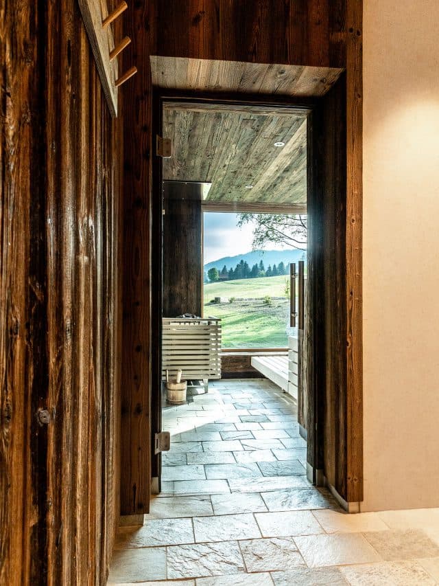 View through the open glass door into the sauna, natural stone floor, the window to the landscape beyond