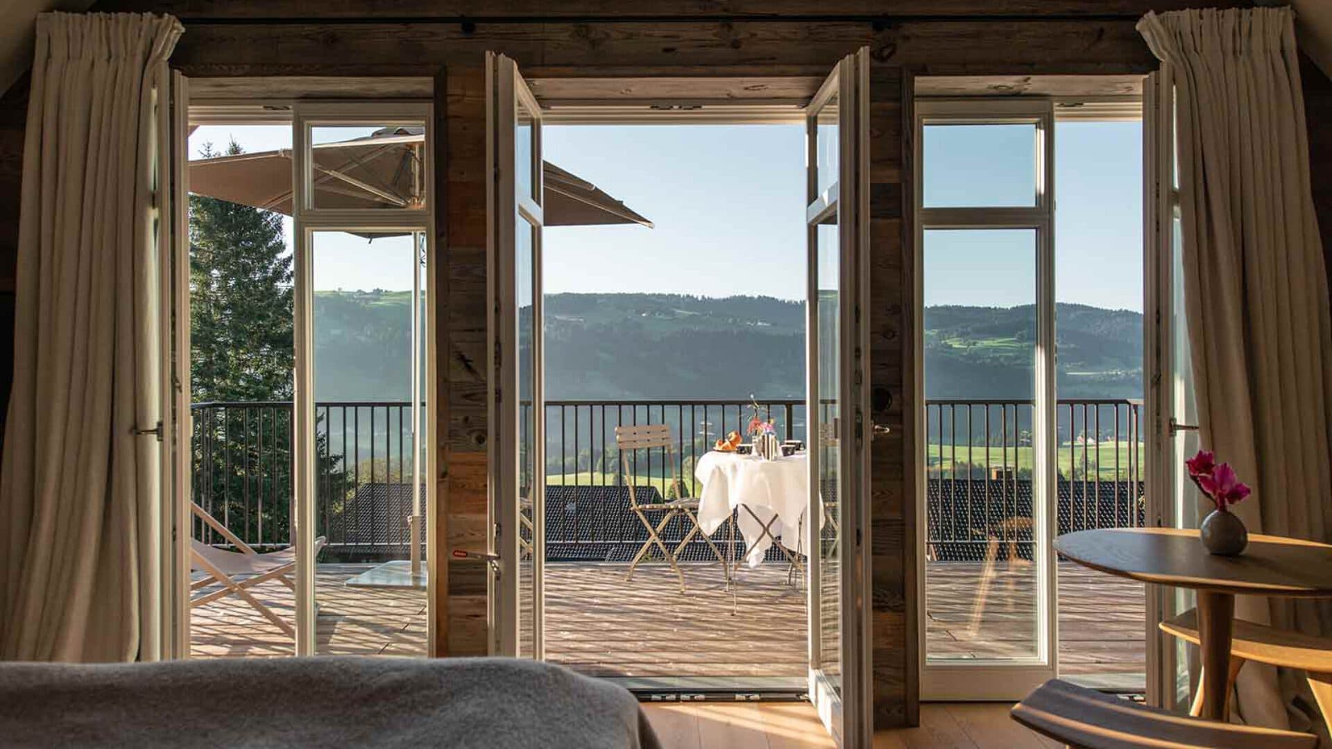 Blick aus der Suite Acht über Wiesen und Hügel bis zu den Bergen