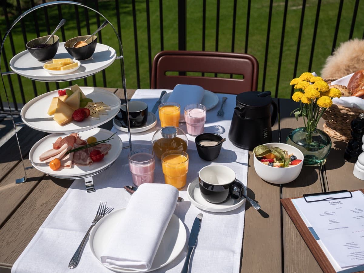 Etagere mit Käse, Aufschnitt und Obst, dazu Säfte und Kaffee