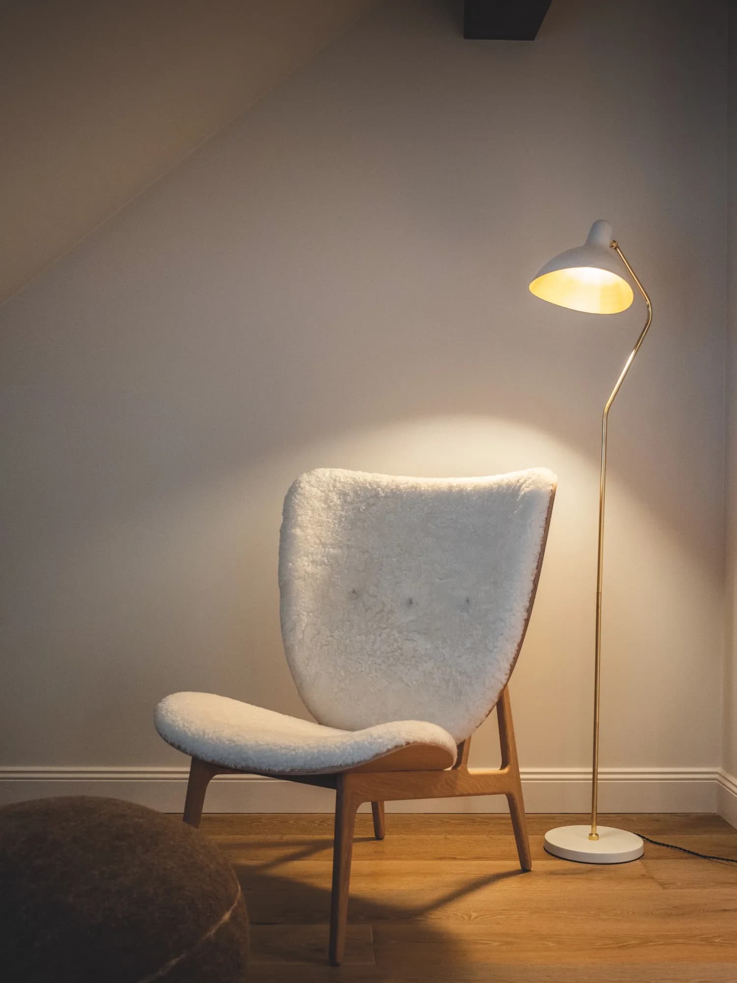 Lammfellbezogener Elephant Chair mit Stehlampe in der Abenddämmerung