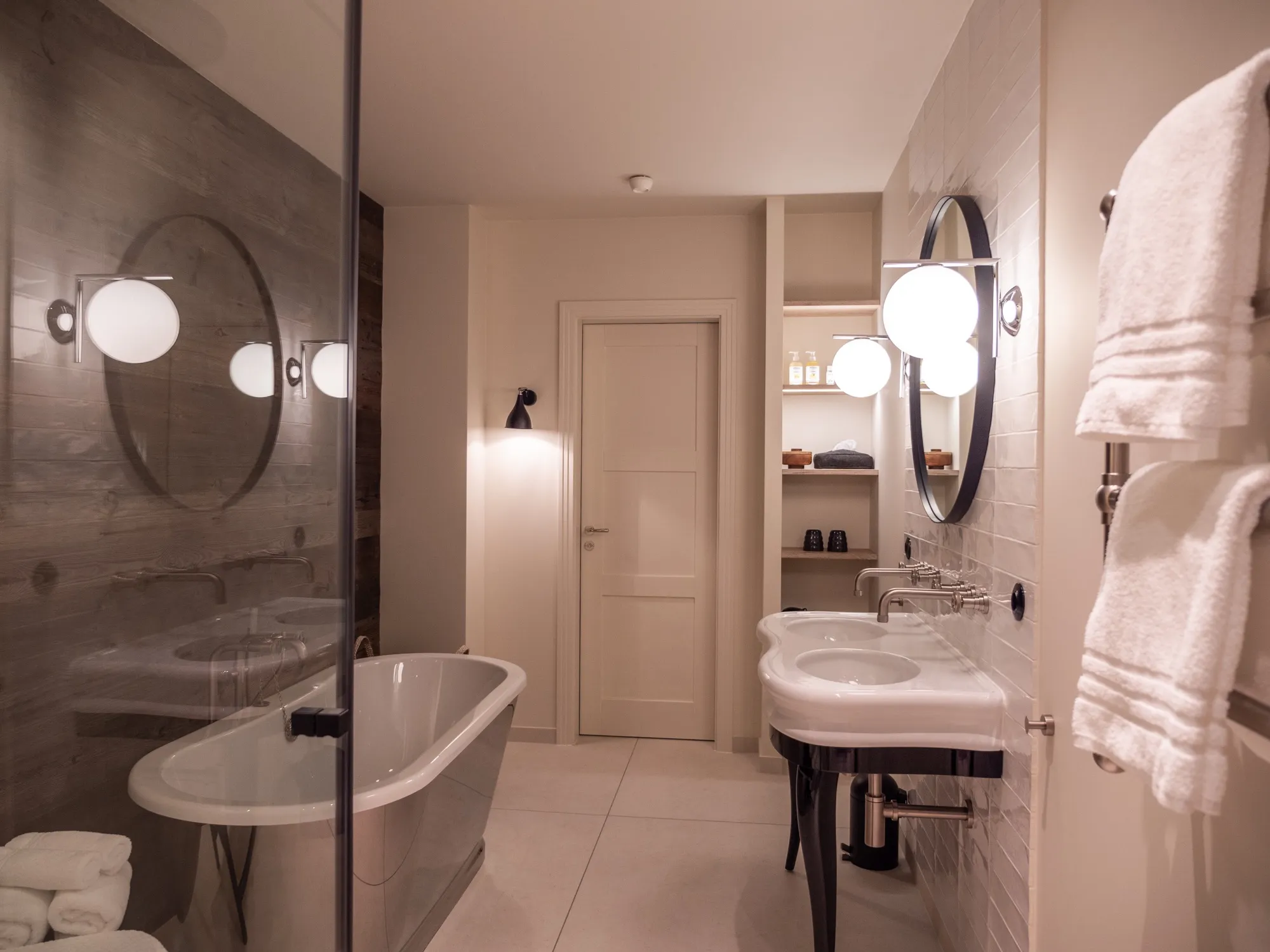 Bad der Suite Acht mit freistehender Wanne, dunklen Fliesen und rundem Wandspiegel