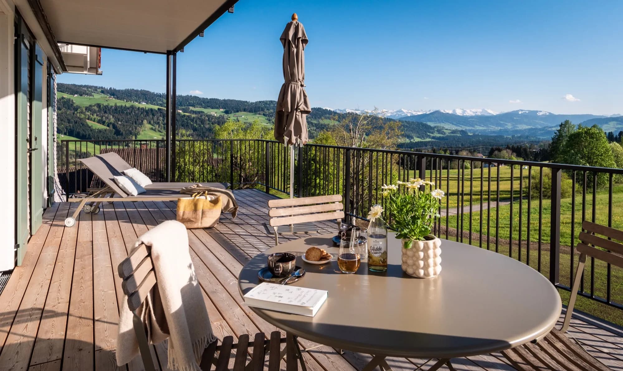 Balkon der Suite Drei mit gedecktem Tisch, Blick über Wiesen bis zu den Alpen