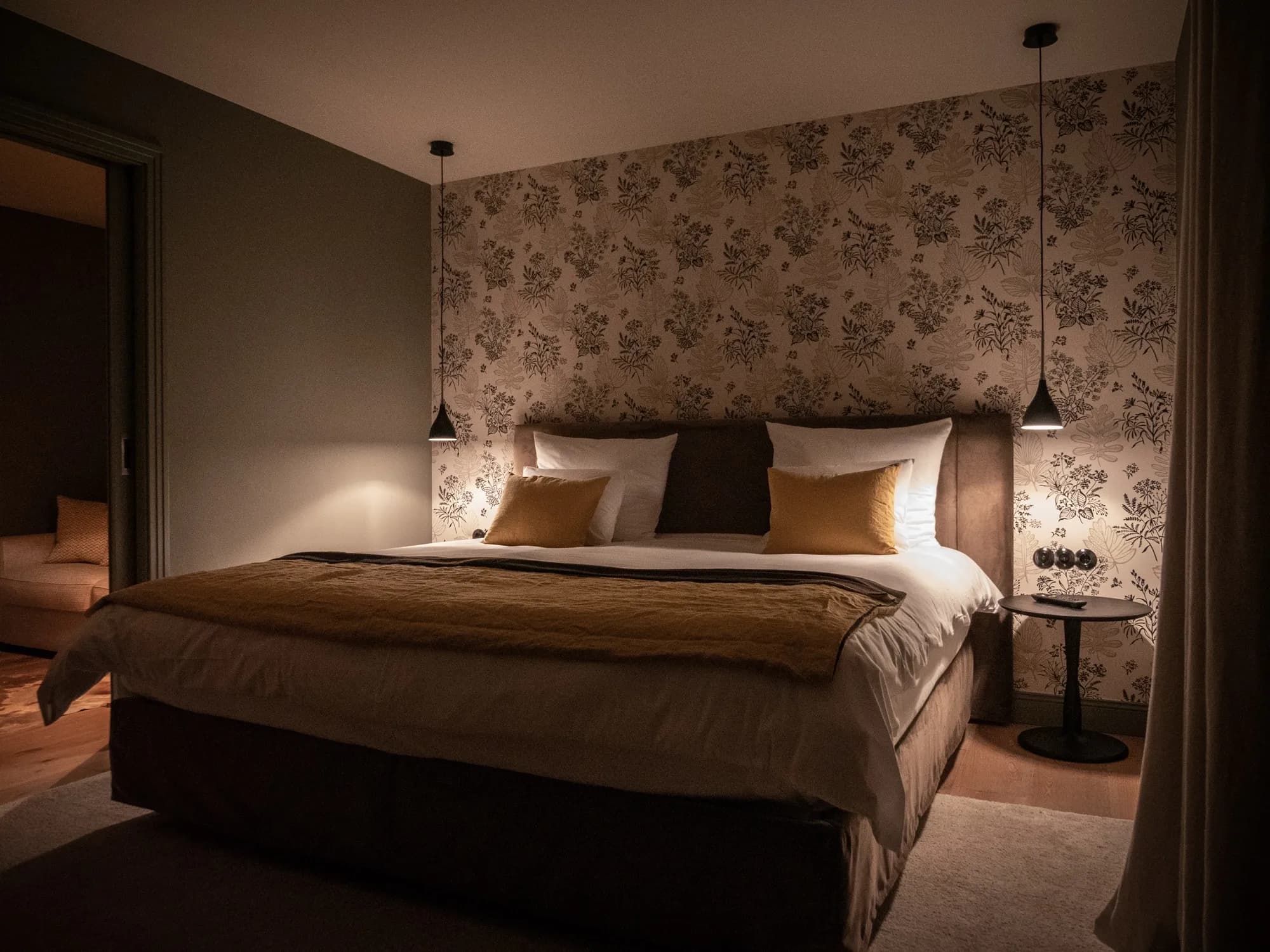 Bett der Suite Drei am Abend, gemusterte Tapete, zwei Pendelleuchten mit warmem Licht