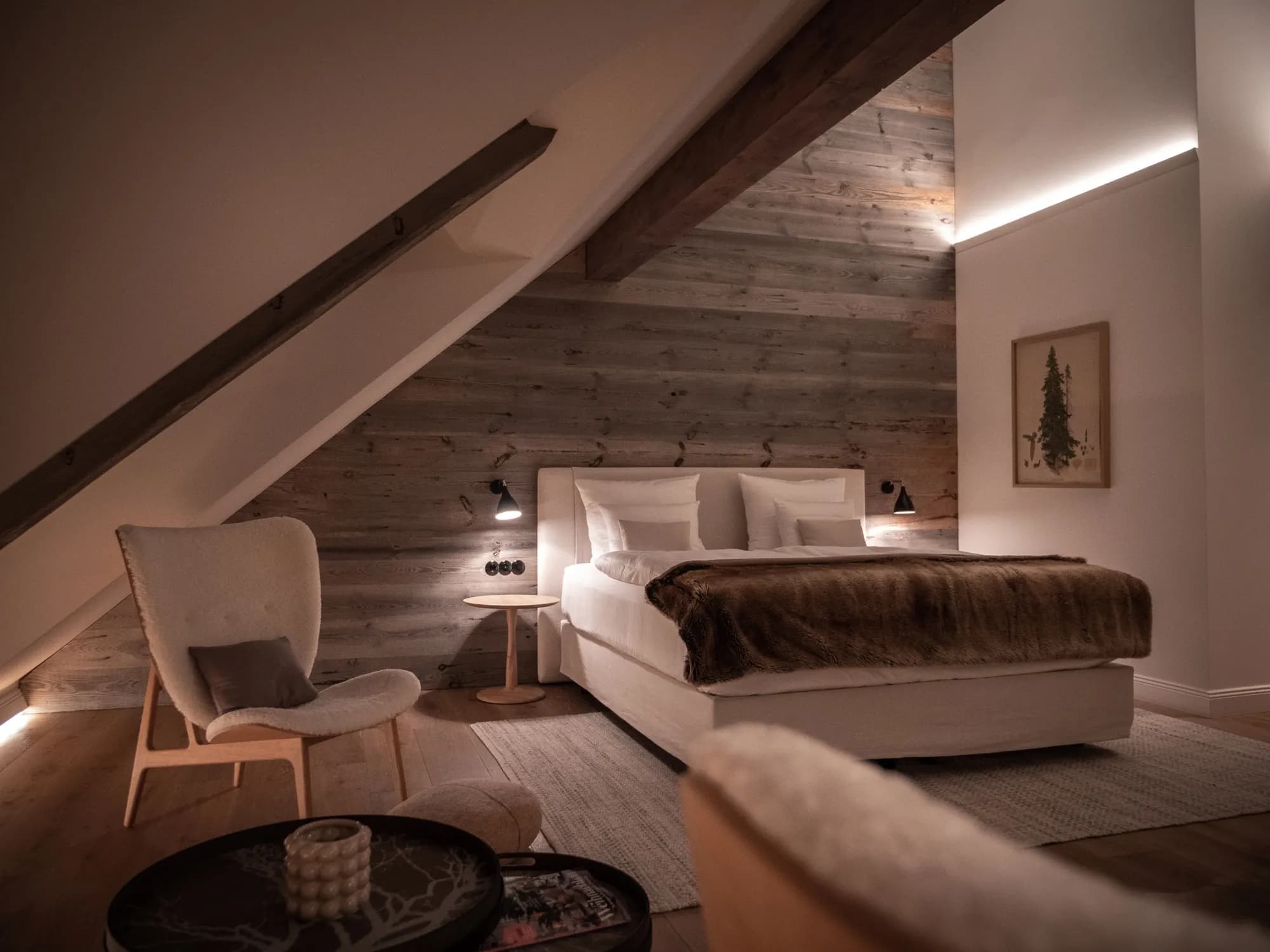 Bett der Suite Neun vor der Altholzwand, Dachbalken über dem Kopfteil
