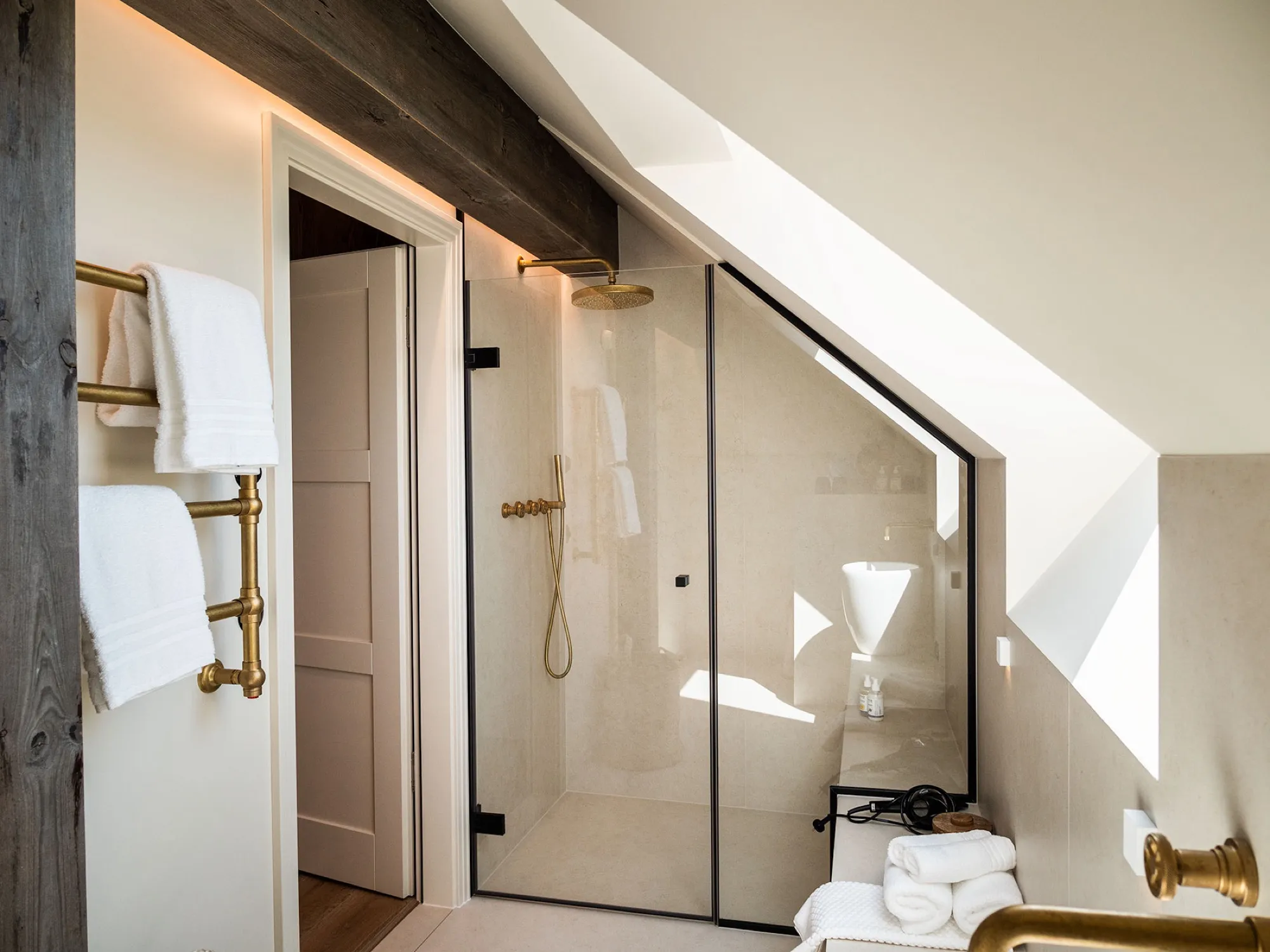 Rain shower beneath the sloping ceiling, brass fittings, plenty of light through the roof window