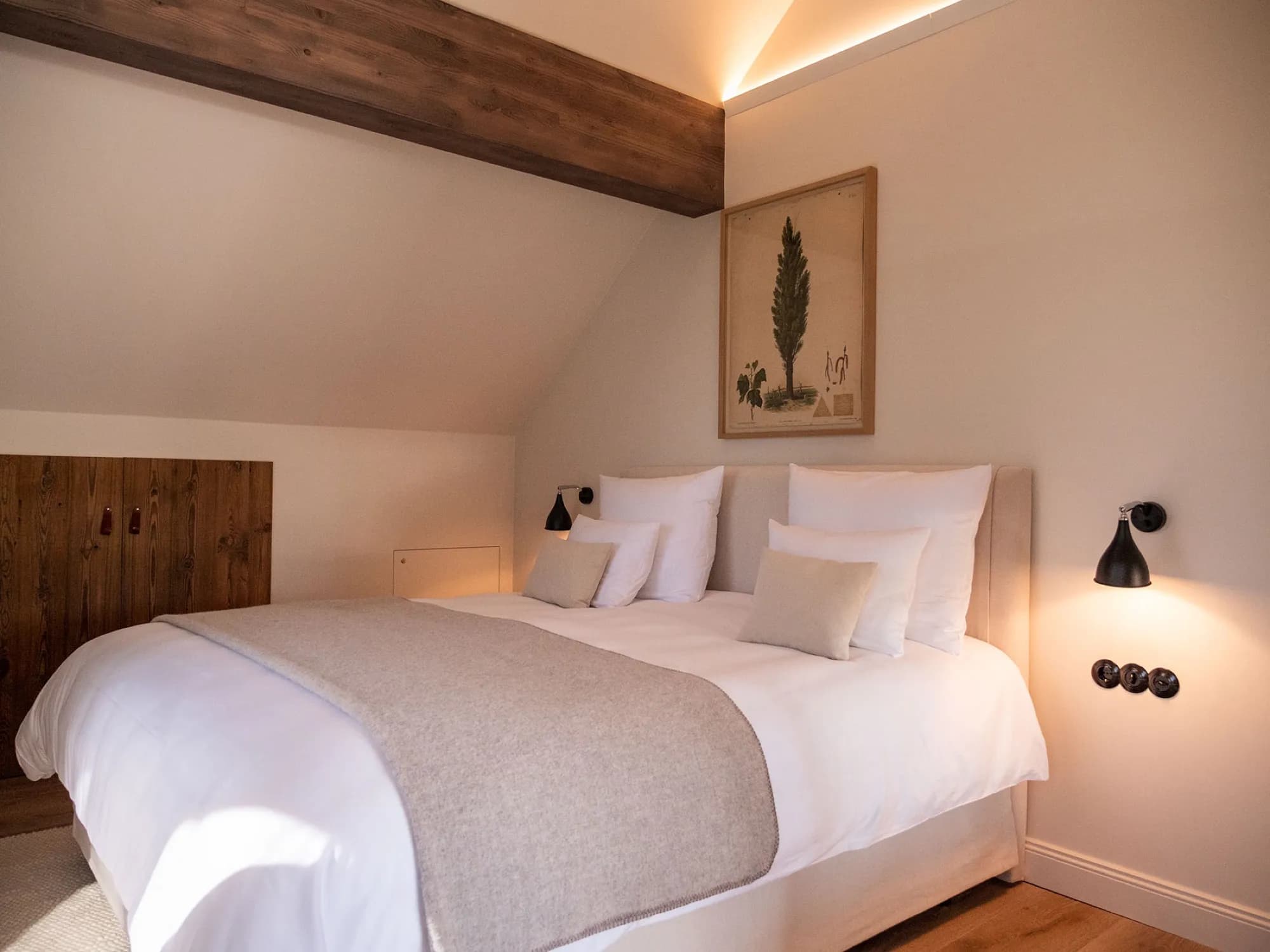 Bett der Suite Sieben unterm Dachbalken, Altholz-Kopfteil, botanisches Bild an der Wand